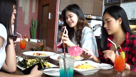 Friends-group-of-one-male-and-three-female-having-lunch-together-and-sharing-something-on-the-phone