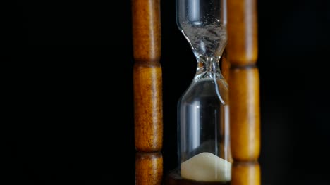 Close-up-View-of-Sand-in-hourglass-or-sandglass-for-time-counting-down.-isolated-on-black-background