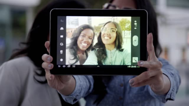 Screen-of-tablet-with-cheerful-multicultural-friends-taking-selfie