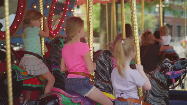 Tres-niñas-riding-en-un-carrusel