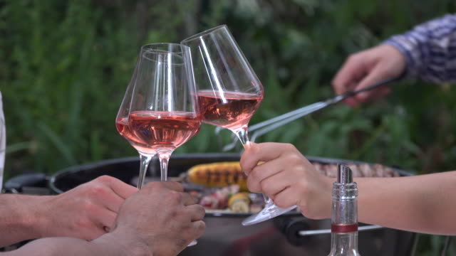 People-having-drinks-outdoors-talking-and-toasting-wine-glasses