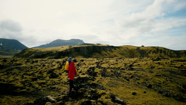 Vista-aérea-de-turistas-caminando-por-el-campo-de-lava-en-Islandia.-Mujer-dos-caminatas-en-la-montaña,-disfrutando-de-la-afición