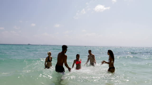 Gente-chapoteando-en-el-agua-que-se-divierten-en-la-playa,-mujeres-y-hombres-alegres-grupo-de-turistas-de-vacaciones
