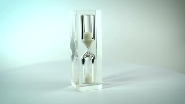 Modern-glass-hourglasses-rotate-against-a-white-background