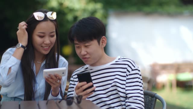 Adolescentes-asiáticos-uso-de-Gadgets-en-el-café-al-aire-libre