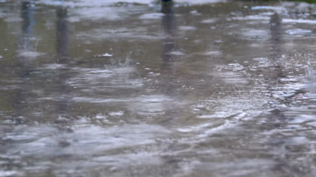 Regentropfen-fallen-auf-dem-Bürgersteig-bilden-eine-Pfütze