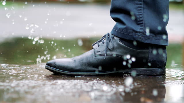 Man-in-black-shoes-stepping-into-the-puddle-in-4k-slow-motion