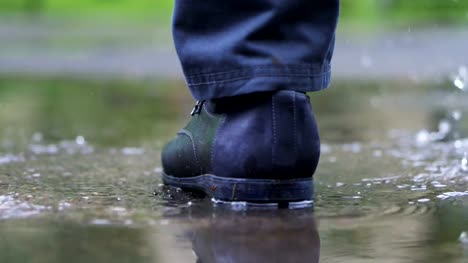 Man-in-black-shoes-stepping-into-the-puddle-in-4k-slow-motion
