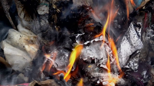 Slow-Motion-Rauch-von-Feuer-brennt-Müll-auf-dunklem-Hintergrund.