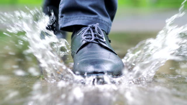 Man-in-black-shoes-stepping-into-the-puddle-in-4k-slow-motion-60fps