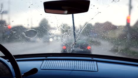 Punto-de-vista-desde-el-asiento-delantero-para-parabrisas-de-coche-retro-viejo-durante-mal-tiempo.-Limpiadores-de-quitar-las-gotas-de-lluvia-desde-la-ventana-del-automóvil-vintage-durante-el-paseo-en-la-carretera.-Cerrar-lenta