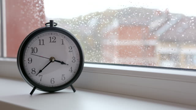 Alte-Retro-Uhr-gegen-Fensterglas-mit-Regen-fällt