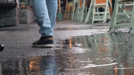 Feet-walk-through-puddle-on-rainy-day-at-outdoor-market