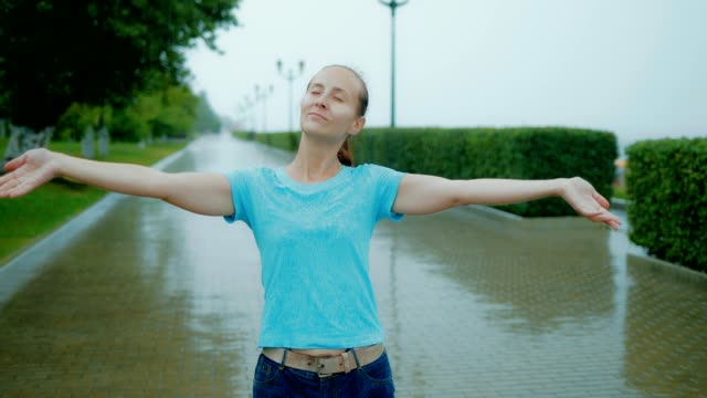 Schöne-Frau-genießt-den-Sommerregen.-Frau-mit-geschlossenen-Augen-und-ihr-Handzeichen-im-Regen-stehen