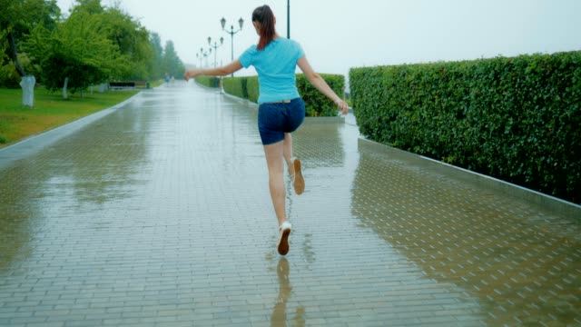 Mujer-feliz-saltando-bajo-la-lluvia-por-el-callejón