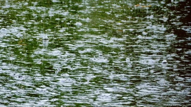 Heavy-tropical-rain-and-raindrops-falling-on-river-pond