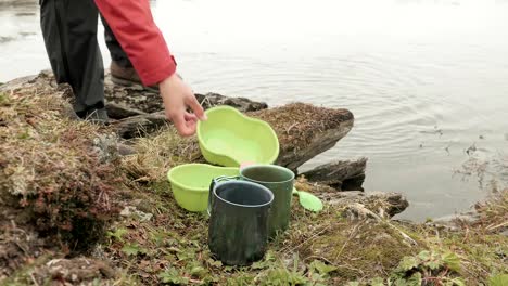 Excursionista-lava-los-platos-en-el-lago.-Noruega