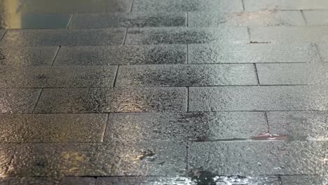 Slow-motion-view-of-raindrops-and-footsteps-of-pedestrians-on-a-sidewalk.