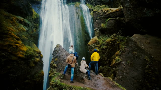 Aerial-view-of-the-group-of-tourist-resting-on-the-top-of-mountain-and-looking-on-the-Gljufrabui-waterfall-in-Iceland