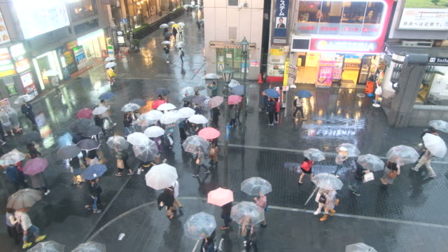 Multitud-de-personas-caminando-con-paraguas-mientras-llueve-en-la-calle-Dotonbori,-Osaka,-Japón