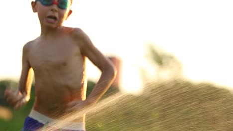 Child-having-fun-with-water-sprinkles-in-slow-motion-60fps-4k-clip-resolution.-Young-boy-by-himself-playing-outside-in-the-lawn-with-water-and-the-simple-things-in-life