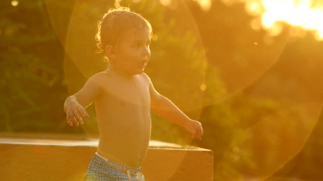 Kinder-Spaß-außerhalb-mit-Wasser-besprengt-bei-Sonnenuntergang.-4-k-Clip-der-Kinder-freuen-sich-über-ihre-Sommerferien-außerhalb-mit-Wasser-besprengt-4K