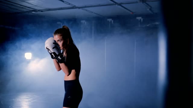Schöne-Kickboxen-Frau-in-Boxhandschuhen-im-Fitness-Studio