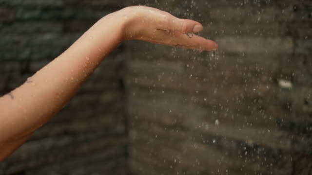 In-the-Shower-Woman-Places-Her-Hand-under-Stream-of-Water.-Droplets-Landing-on-Her-Palm.