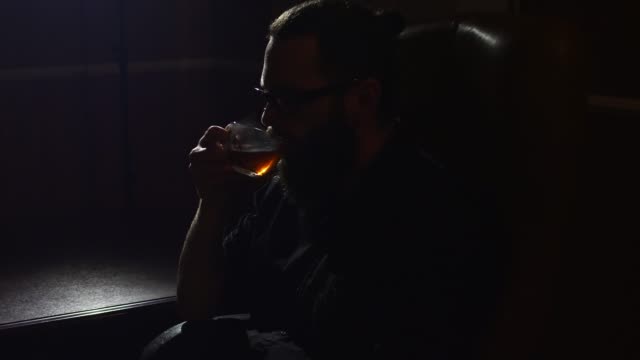 Young-bärtiger-Mann-in-Gläsern-Getränke-Tee-in-Shisha-Lounge-Zimmer-Nahaufnahme-auf-schwarzem-Hintergrund-in-Zeitlupe-in-4k