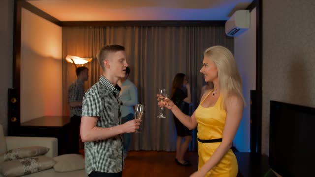 Young-couple-have-private-conversation-and-flirt-at-glamorous-party-drinking-champagne-cocktail