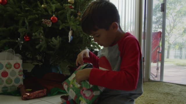 Lento-movimiento-de-un-niño-abriendo-regalos-el-día-de-Navidad,-pero-no-está-seguro-de-lo-que-es