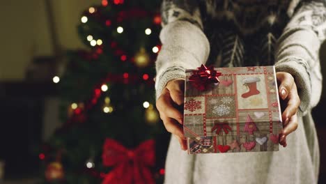 Mädchen-mit-weihnachtsmütze-macht-Wünsche-und-öffnet-ein-Weihnachts-Geschenk-Paket.-Konzept-der-Feiertage-und-Neujahr.-Das-Mädchen-freut-sich-und-lächelt-mit-Weihnachts-Geschenk-in-der-hand.