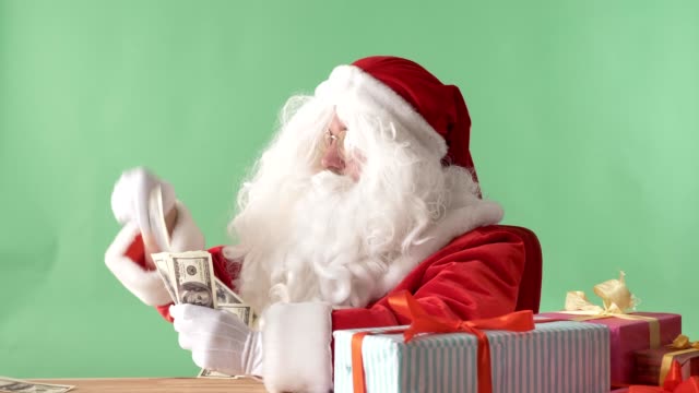 Zufrieden-Weihnachtsmann-werfen-Rechnungen-aus-einem-Bündel-Geld-auf-Tisch,-Geld-Konzept,-Chromakey-im-Hintergrund