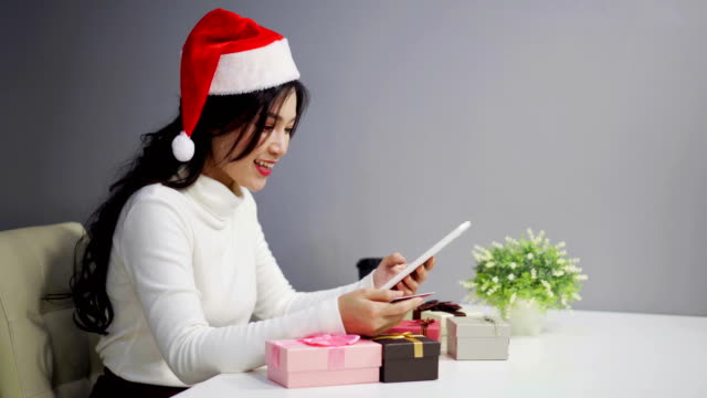 glückliche-Frau-in-Santa-Hut-Online-shopping-für-Weihnachtsgeschenk-mit-digital-Tablette