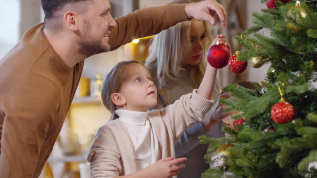 Mutter-und-Vater-dekorieren-Weihnachtsbaum-mit-kleinen-Kindern