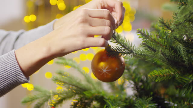 Hände-von-Frau-schmücken-Weihnachtsbaum-mit-Weihnachtskugel