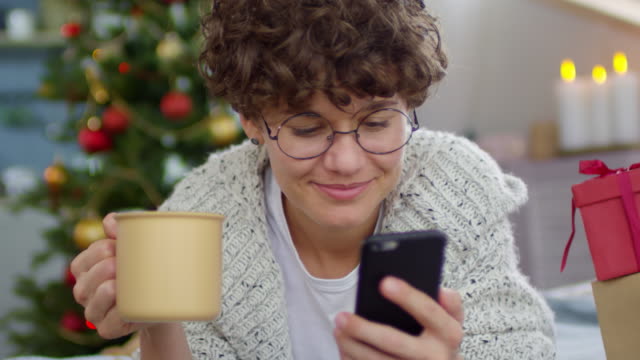 Glückliche-Frau-mit-Handy-zu-Weihnachten
