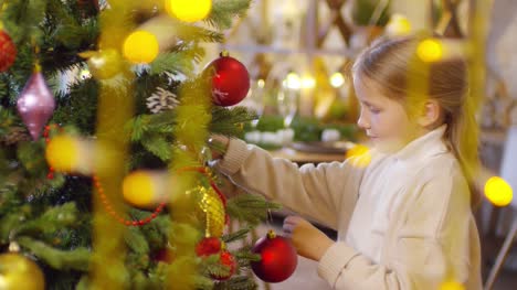 Adorable-niña-decoración-árbol-de-Navidad-con-guirnaldas