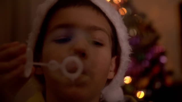 Junge-in-Seifenblasen-auf-dem-Hintergrund-eines-Baumes-Neujahr-Weihnachtsmann-Mütze