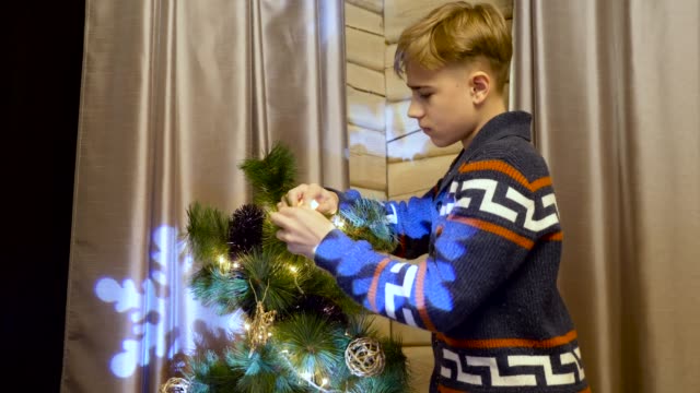 kleiner-Junge-putting-Weihnachten-Spielzeug-auf-dem-Baum-in-der-Heiligabend,-Schneeflocken-im-Hintergrund,-Nahaufnahme