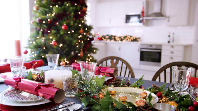Ein-Esstisch-vorbereitet-für-Weihnachtsessen-mit-einem-Weihnachtsbaum-und-Küche-Hintergrund-bokeh