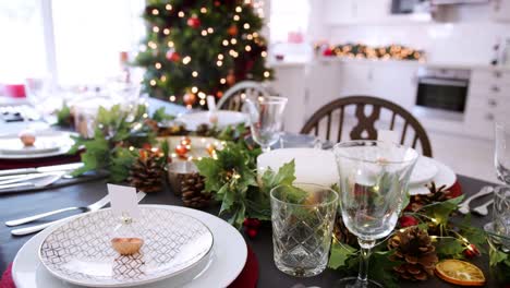 Eine-Nahaufnahme,-langsame-panning-Shot-zeigt-ein-festlicher-Weihnachten-Esstisch-mit-Christbaumkugel-Name-Karteninhaber-auf-Tellern-arrangiert-und-grüne-und-rote-Saisondekorationen