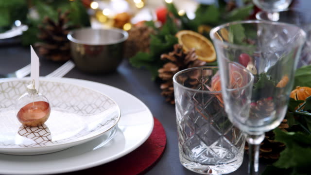 Schwenken-in-der-Nähe-der-Weihnachtskugeln-auf-einem-Teller-auf-einem-Esstisch-dekoriert-für-Weihnachtsessen,-selektiven-Fokus