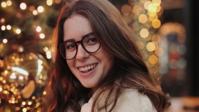 Girl-have-fun-near-Christmas-tree-and-smile-to-camera