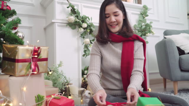 Lesben-Asian-paar-Weihnachtsgeschenke-geben-einander-in-ihrem-Wohnzimmer-zu-Hause-in-Christmas-Festival.-Lebensstil-Lgbt-Frauen-glücklich-feiern-Weihnachten-und-Neujahr-Konzept.