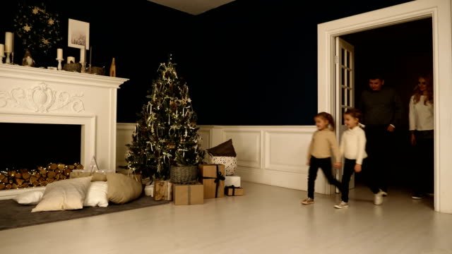 Glückliche-Familie-Spaziergänge-im-Wohnzimmer,-die-Geschenke-unter-dem-Weihnachtsbaum-zu-überprüfen