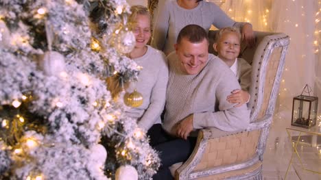 Smiling-family-having-fun-near-decorative-New-Year-tree-at-holiday-in-cozy-home