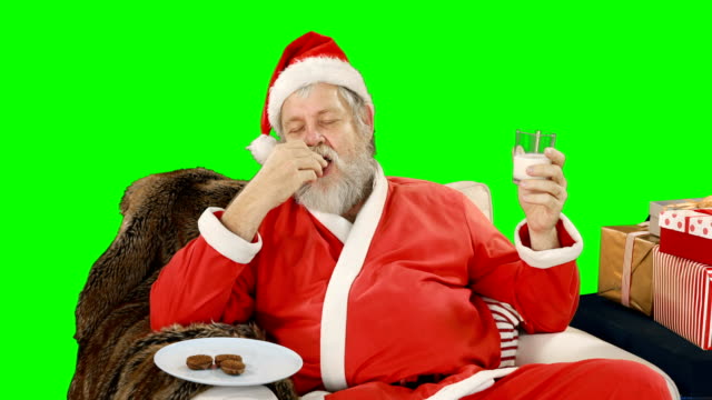 Santa-claus-relaxing-on-couch-and-having-sweet-food
