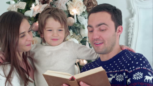 Feliz-familia-de-tres-lecturas-juntos-en-la-noche-de-Navidad