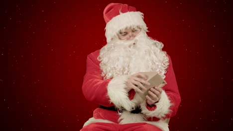 Weihnachtsmann-mit-Weihnachtsbrief-oder-Wunschliste-auf-rotem-Hintergrund-mit-Schnee